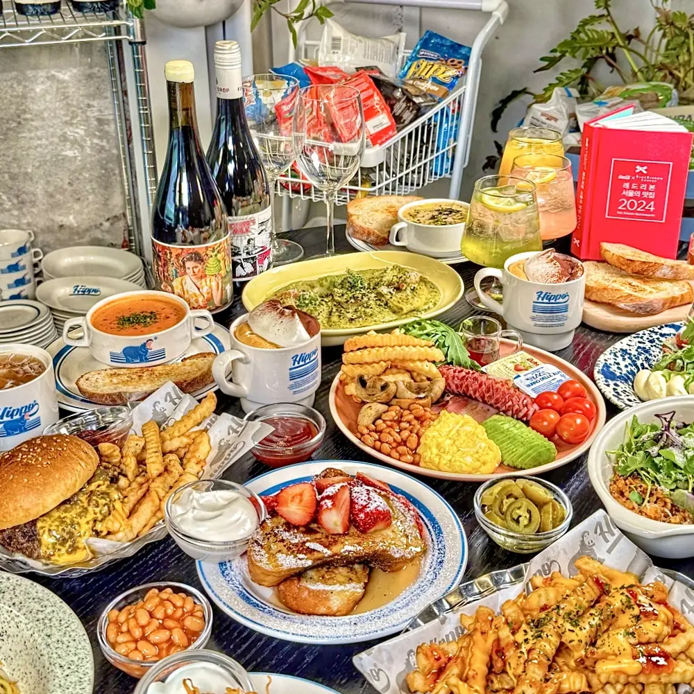 A large spread of brunch dishes with wine and the Blue Ribbon Survey 2024 guidebook on the table