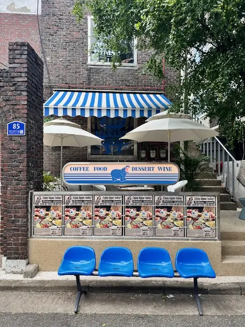 The blue-striped awning, parasols and blue bench outside Hippo Brunchaus at 85 Seongmisan-ro 17-gil
