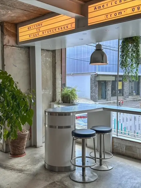 Window bar seating and stools under the 'Welcome to Hippo Brunchhaus' sign — an easy spot for solo brunch